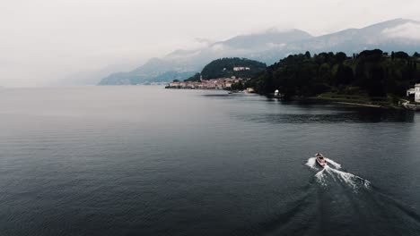 Toma-De-Drones-De-Un-Barco-Que-Pasa-Por-Un-Tranquilo-Lago-De-Como-A-Mitad-Del-Día.