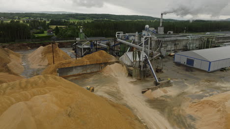 Loader-Hauling-Heap-Of-Sawdust-At-Lumber-Factory-In-Braskereidfoss,-Norway
