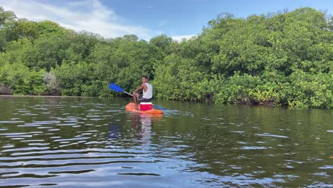Tribal-black-man-guiding-some-tourist-kayaking-in-tropical-mangroves-river