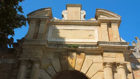 Low-angle-shot-of-details-of-carved-facade-of-an-Italian-medieval-town-entrance-in-Urbino,-Italy-on-a-sunny-day
