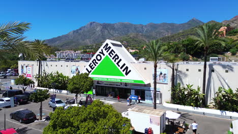 Aerial-view-of-Leroy-Merlin-home-improvement-and-gardening-retailer,-big-hardware-store-parking-with-palm-trees-in-Marbella-Malaga-Spain,-4K-shot