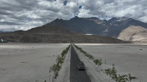 Imágenes-De-Drones-Volando-Hacia-Atrás-De-Un-Automóvil-Conduciendo-Por-Una-Hermosa-Carretera-Dentro-De-Una-Montaña-En-La-Zona-Norte-De-Pakistán