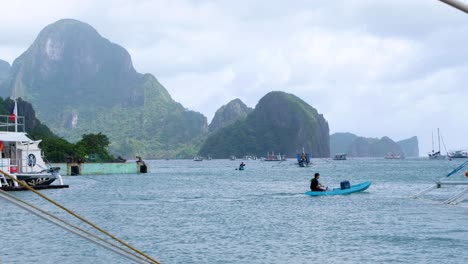 Scenic-ocean-view-of-kayakers-and-island-hopping-tour-boats-with-stunning-tropical-islands-in-the-distance-at-El-Nido,-Palawan,-Philippines