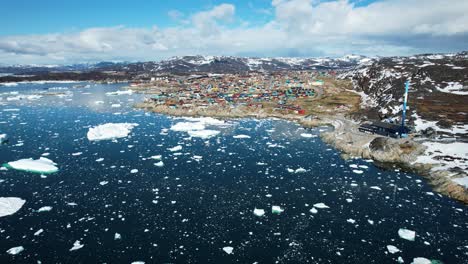 Shoreline-township-of-Ilulissat-in-Greenland-with-floating-icebergs,-aerial-view