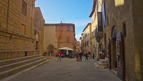 People-Walking-By-And-Dining-By-The-Entrance-Of-San-Francesco-Church-In-Pienza,-Siena,-Italy