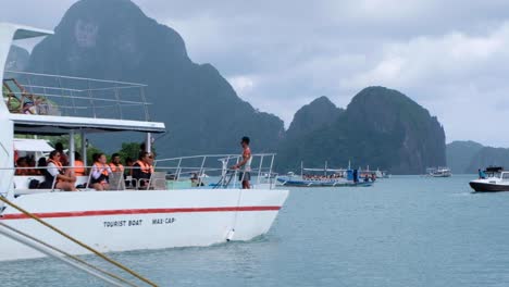 Tourist-wearing-life-jackets-on-large-island-hopping-tour-boat-with-scenic-view-of-beautiful-tropical-islands-in-El-Nido,-Palawan,-Philippines