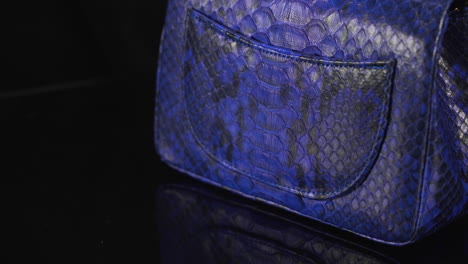 Exótico-Bolso-Chanel-De-Piel-De-Serpiente-Azul-Girando-Con-Fondo-Negro-Oscuro,-Costoso-Producto-De-Lujo-Hecho-De-Cuero-Real,-Toma-De-4k