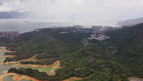 Luftaufnahme-Einer-Bewaldeten-Landschaft-Neben-Dem-Tai-Lam-Chung-Stausee-Mit-Stadtbildgebäude-Im-Hintergrund-In-Hongkong