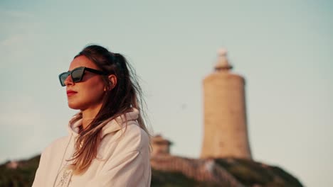 Slow-motion-shot-of-a-female-wearing-sunglasses-watching-the-sunset-over-the-ocean