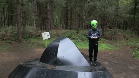 Gracioso-Extraterrestre-Dando-Signo-De-Paz-De-Pie-Sobre-Un-Platillo-Volador-En-El-Bosque-De-Rendlesham