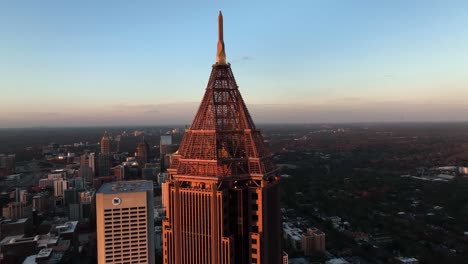 Rascacielos-Superalto-Bank-Of-America-Plaza-Forma-Piramidal-En-La-Parte-Superior-Con-Otros-Edificios-Del-Horizonte-Al-Atardecer,-Vista-Aérea