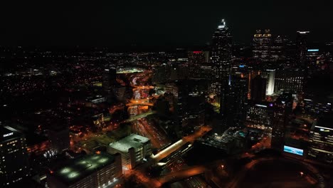 Drone-shot-of-Downtown-Atlanta-skyscrapers-at-night,-Traffic-movement-across-the-freeway