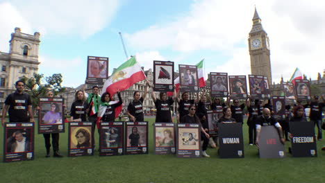 Protestors-in-front-of-Big-Ben,-wearing-black-“Woman-Life-Freedom”-T-shirts-hold-placards-of-Mahsa-Amini-and-other-people-killed-during-women’s-rights-and-pro-democracy-protests-in-Iran