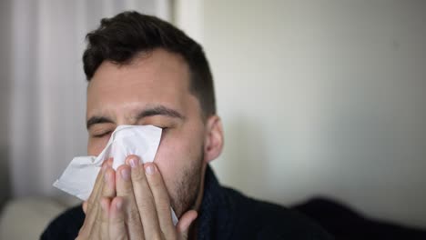 Young-gay-man-blowing-nose-and-coughing,-sick-at-home-with-Covid