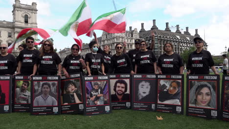 Demonstranten,-Die-Schwarze-„Woman-Life-Freedom“-T-Shirts-Tragen,-Halten-Plakate-Mit-Mahsa-Amini-Und-Anderen-Menschen,-Die-Bei-Protesten-Für-Frauenrechte-Und-Pro-Demokratie-Im-Iran-Getötet-Wurden