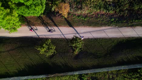 Cool-overhead-view-of-cyclists-casting-long-shadows-on-beautiful-bike-trail,-4K-30p