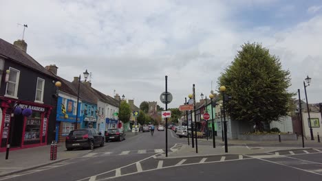 Mann-Auf-Einem-Fahrrad-In-Einer-Kleinen-Stadt-Im-Ländlichen-Irland,-Der-An-Einem-Sommermorgen-Die-Hauptstraße-Hinaufradelt