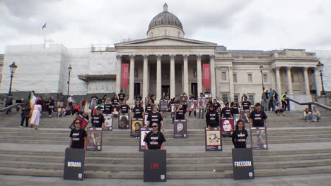 Protesters-holding-placards-that-depict-Mahsa-Amini-and-others-that-have-been-killed-in-women’s-rights-protests-in-Iran-stand-on-steps-in-front-of-the-National-Gallery-in-Trafalgar-Square
