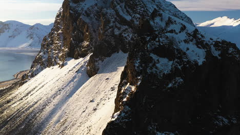 Aerial-tracking-shot-of-a-snowy-mountain-ridge,-winter-evening-in-southern-Iceland