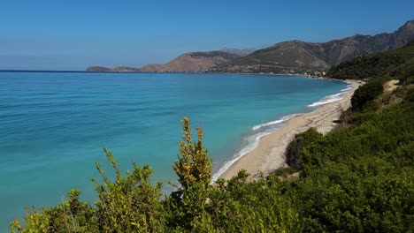 Paradise-Beach-Sheltered-by-Verdant-Hills-in-Albania,-Overlooking-the-Azure-Mediterranean-Sea-for-Ultimate-Relaxation-and-Vacation-Bliss
