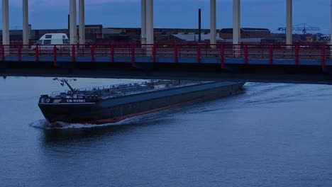 Mientras-Cae-La-Oscuridad,-El-Barco-Cisterna-En-avant-Navega-Bajo-El-Puente-Del-Río-Noord