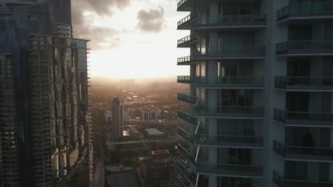 Luftdrohnen-Fliegen-Um-Wolkenkratzer-Glasbalkone-In-Der-Innenstadt-Von-Miami,-Hintergrund-Der-Skyline-Bei-Sonnenuntergang