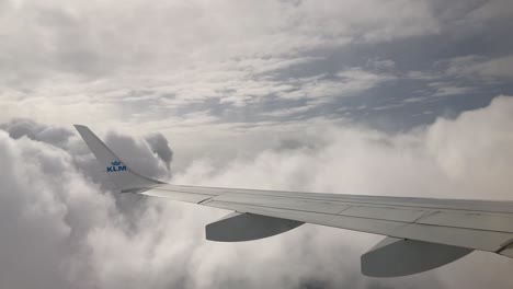 Wing-of-a-KLM-airplane-in-the-clouds-in-mid-air-flight