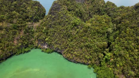 Hong-Island-Lagoon,-Krabi-Thailand-with-boat-and-green-water-surrounded-by-tropical-tree-covered-cliffs--aerial-perspective