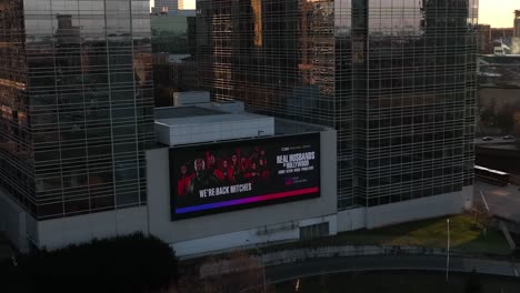 Real-Husbands-of-Hollywood-advertisement-on-Downtown-Atlanta-Peachtree-Street-Billboard,-Sunlight-falling-on-glass-buildings