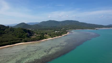 Koh-Samui-Thailand-tropical-island-coastline-with-reefs,-beach-and-blue-ocean-water-on-sunny-day-with-blue-skies---aerial-view
