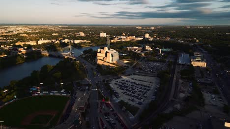 Ein-Gebäude-Schatten-Sonnenuntergang-Goldene-Stunde-Luftaufnahme-Des-Stadtparks-Kanadisches-Museum-Für-Menschenrechte-The-Forks-Market-Innenstadt-Von-Winnipeg-Shaw-Park-Provencher-Bridge-Red-River-In-Manitoba-Kanada