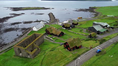 Kirkjubour-green-village-with-turf-houses-and-Magnus-Cathedral-ruins-on-coast-of-Streymoy,-Faroe