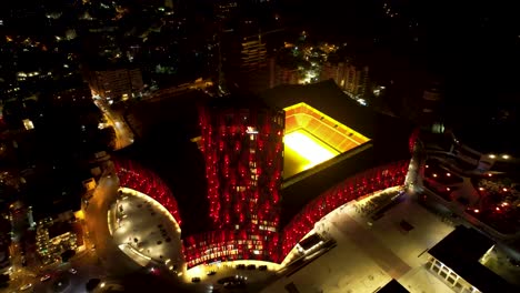 El-Vibrante-Paisaje-Nocturno-De-Tirana:-Vista-Aérea-Con-Drones-De-La-Colorida-Fachada-Del-Estadio-Iluminada-En-La-Gloria-Nocturna-De-La-Ciudad-Capital