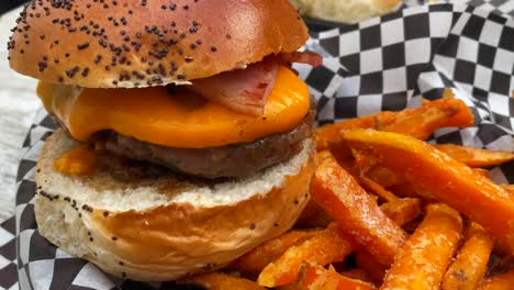 Tasty-cheeseburger-with-bacon,-a-brioche-bun-and-sweet-potato-fries,-unhealthy-American-food,-4K-shot