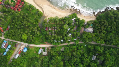 A-road-among-trees-and-some-cottages-stretches-along-the-coast-of-Phi-Phi-Islands,-Thailand