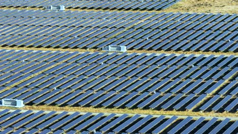 Toma-Aérea-De-Paralaje-De-Paneles-Fotovoltaicos-Alineados-En-Una-Granja-Solar-En-Mojave