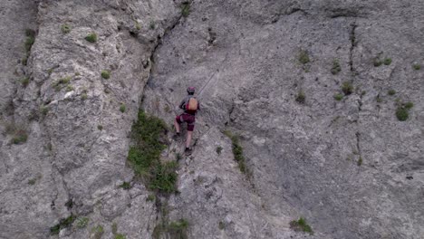 reveal-of-giant-mountain-cliff-on-which-a-person-is-doing-a-via-ferrata