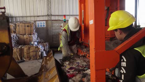 Two-workers-load-a-bale-of-non-recyclable-waste-onto-a-bulldozer-for-final-disposal