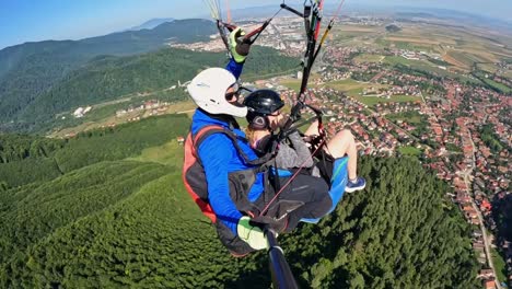 Couple-explores-new-city-from-unique-perspective-of-paragliding-high-in-sky,-panoramic-forested-valleys-and-cityscape
