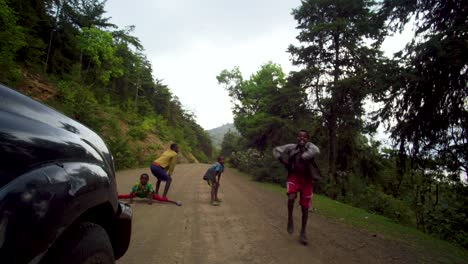 Young-African-Boys-Dancing-In-Front-Of-Driving-Vehicle-To-Earn-Money-In-Omo-Valley,-Ethiopia