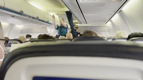 Passenger-Point-of-View-of-WestJet-Flight-Attendant-Signaling-Safety-Exit-Locations-to-Passengers-on-WestJet-Airplane-at-LAX-Airport-on-7-13-2023