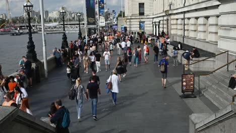 People-walking-past-the-London-Eye-along-Queens-Walk,-London,-United-Kingdom