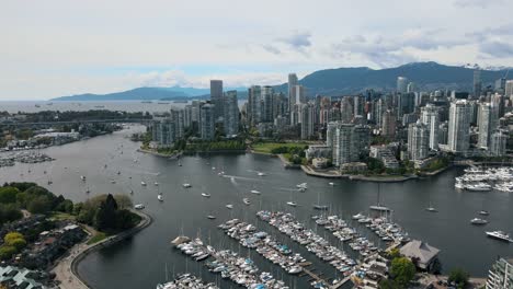 Aerial-establishing-shot-of-Vancouver-City-Skyline-with-high-rise-buildings-and-parking-boats-and-yachts-at-falls-creek-pier,-Canada---descending-flight