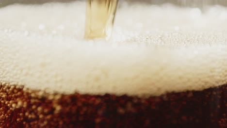 Macro-view-of-cola-soda-being-poured-in-glass-and-surface-rising