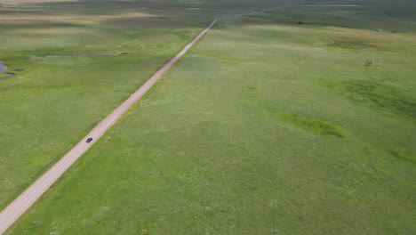 Aerial-View-of-Car-Driving-Down-a-Road-in-the-Middle-of-Nowhere