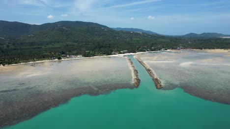 Koh-Samui-Thailand-Boat-Harbor-canal-with-blue-tropical-water-at-low-tide---aerial-fly-in-to-boats-docked-and-houses-alone-shore