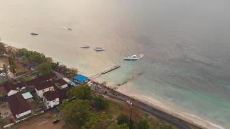 Wide-shot-of-fast-ferry-at-Nusa-Penida-docked-near-beach,-aerial
