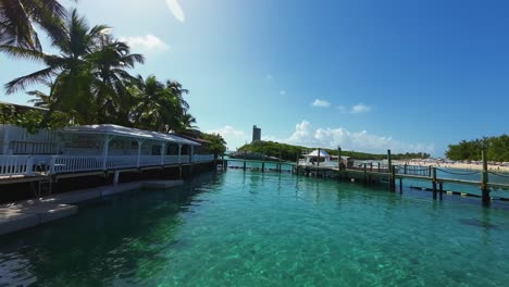 Tilt-up-wide-action-cam-shot-revealing-a-beautiful-tropical-Caribbean-island-with-wooden-bridges-over-water,-palm-trees,-and-crystal-clear-turquoise-water-in-the-Bahamas-on-a-sunny-warm-day