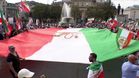 Demonstranten-Halten-Eine-Riesige-Iranische-Flagge-Während-Einer-Protestkundgebung-Auf-Dem-Trafalgar-Square-Anlässlich-Des-Einjährigen-Todestages-Von-Mahsa-Amini