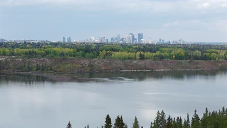 An-aerial-drone-flies-towards-the-City-of-Calgary-over-the-tree-lined-Glenmore-reservoir-during-autumn
